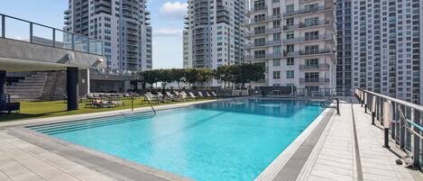 A swimming pool with a tiled deck, surrounded by high-rise residential buildings.