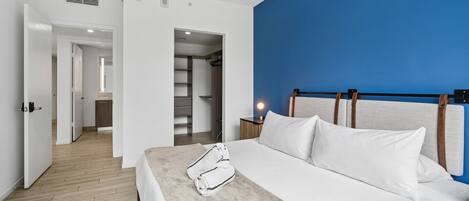 Une chambre d’hôtel moderne avec un lit, une table de chevet et un mur d’accent bleu.