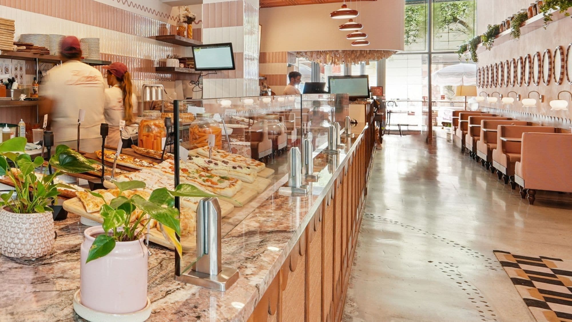 A buffet area with a variety of food items, a counter with staff, and seating area with tables and chairs.