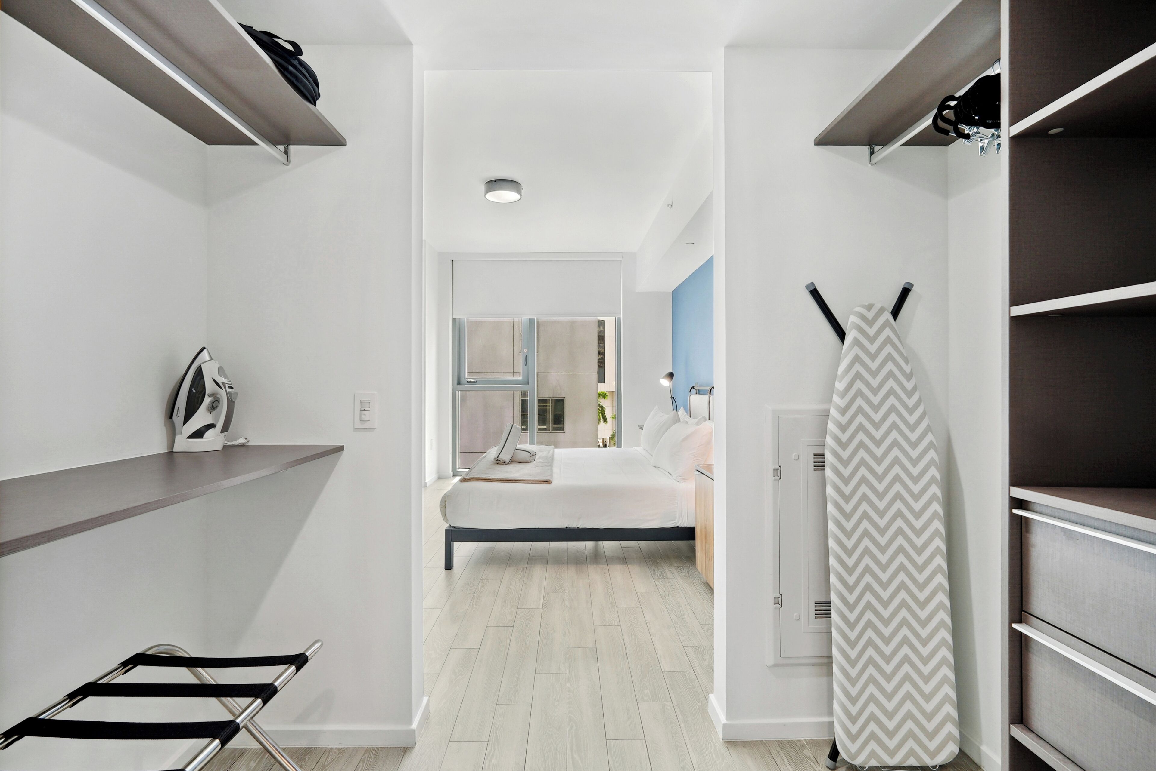 Een moderne slaapkamer met een bed, een wasrek en een uitzicht op een stadsgezicht door een raam.