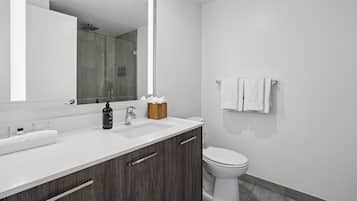 A modern bathroom with a white sink, dark wood cabinets, a large mirror, and a toilet.