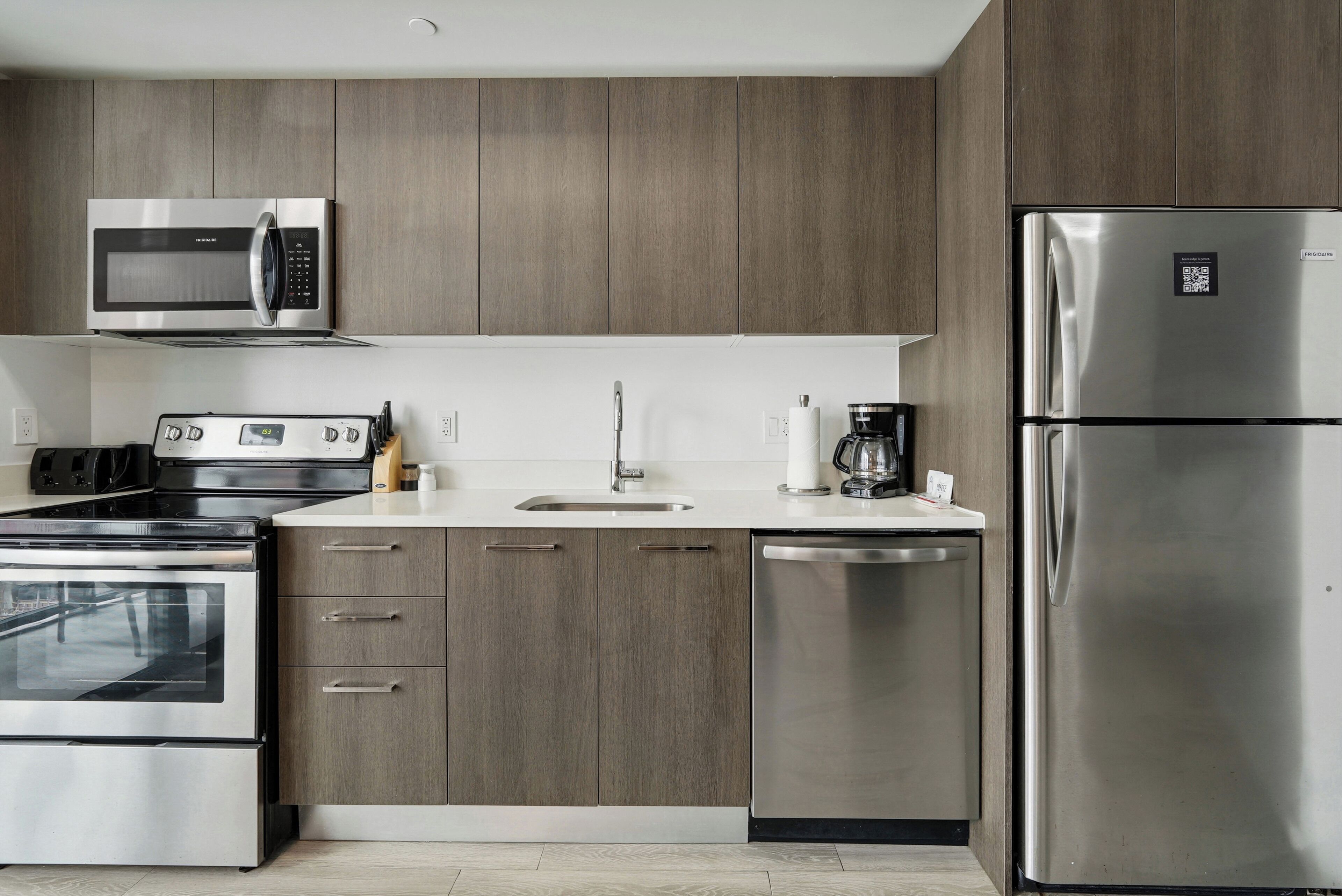 Una cocina moderna con electrodomésticos de acero inoxidable, armarios de madera, horno integrado y lavavajillas.