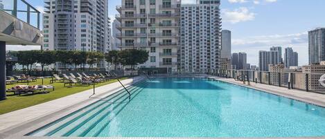 A swimming pool with lounge chairs and a view of high-rise buildings.