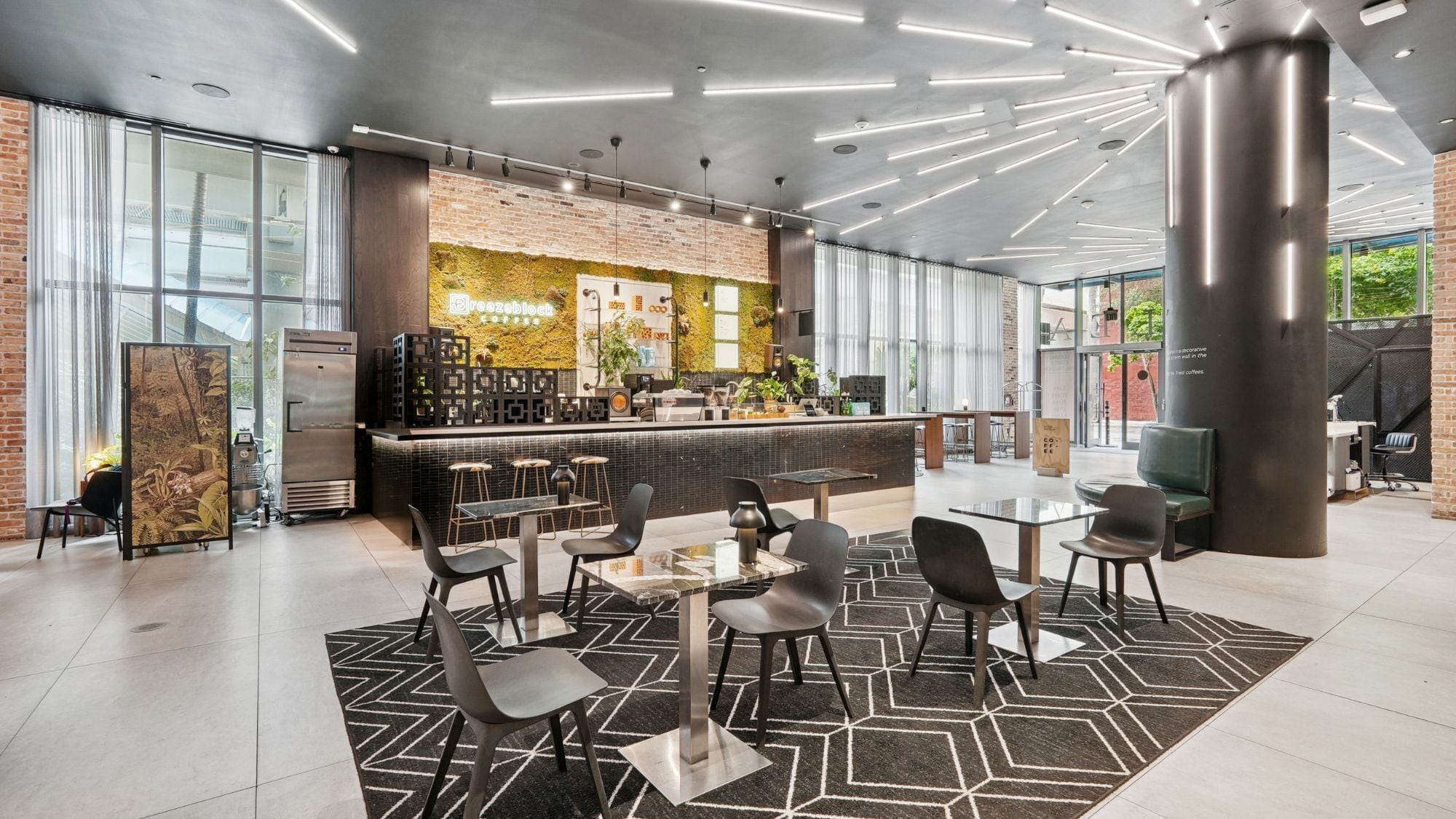 A modern coffee shop with a brick wall, a bar area, and seating arrangements.