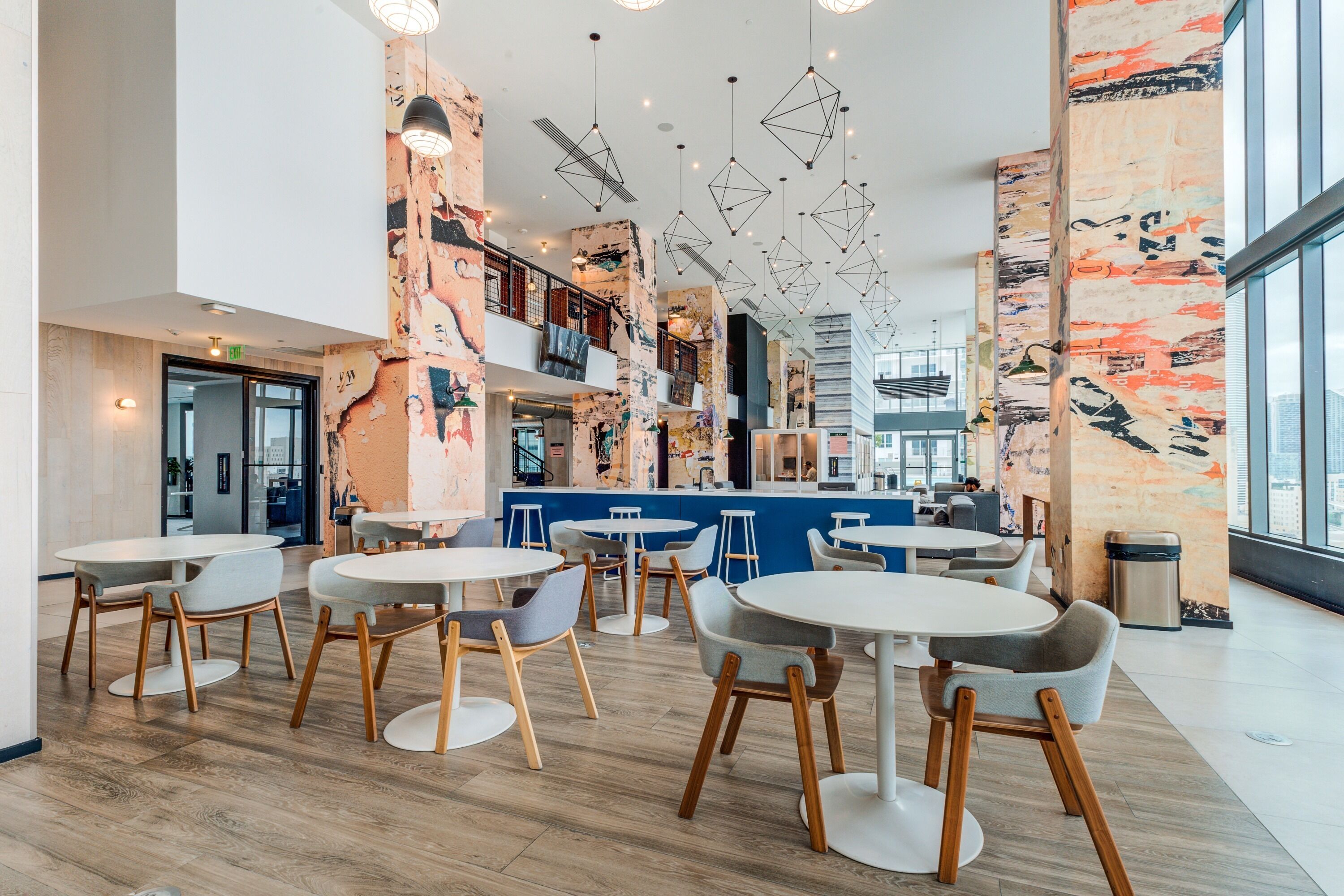 Un intérieur moderne avec des tables et des chaises rondes, un coin bar et une vue dégagée grâce à de grandes fenêtres.
