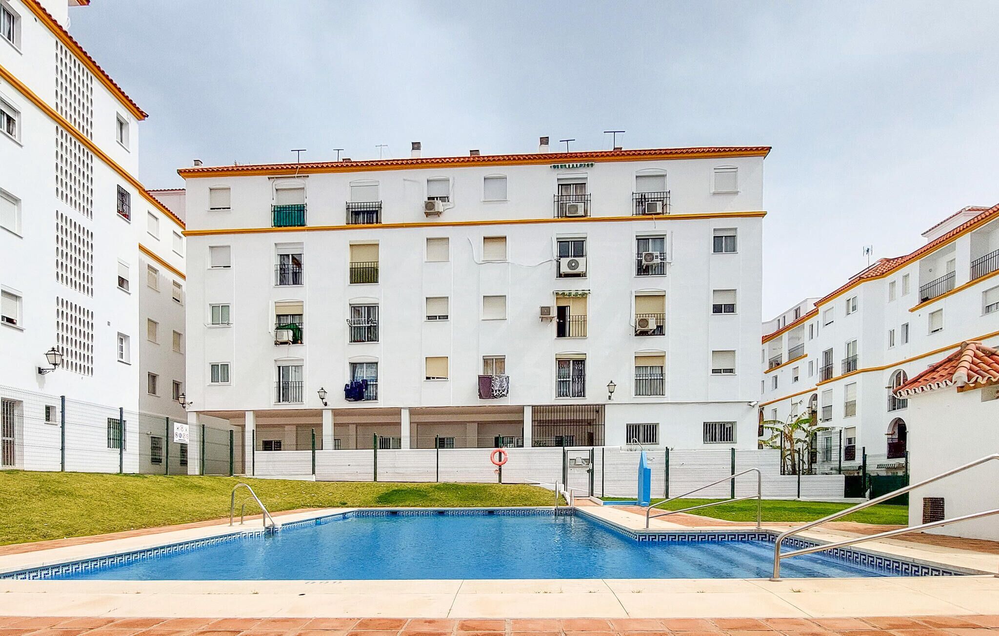 A multi-story residential building with a swimming pool in the foreground.