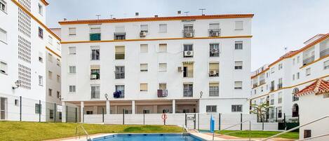 A multi-story residential building with a swimming pool in the foreground.