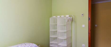A bedroom with a bed, a white wall unit with shelves, and a door.