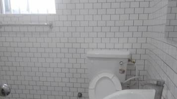 A bathroom with white tiled walls and floor, a toilet, a sink, and a checkered floor.