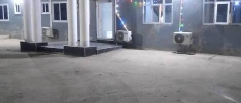Un edificio con un área de entrada techada, unidades de aire acondicionado y una fuente de luz brillante.