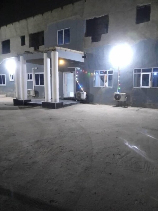 A building with a covered entrance area, air conditioning units, and a bright light source.
