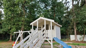 A wooden playhouse with a slide, surrounded by trees. - 1 bedroom beach front home in Pobierowo (Pobierowo)