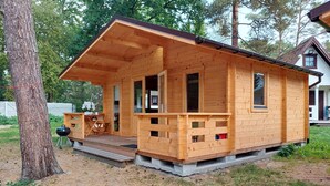 A wooden cabin with a porch, a grill outside, and a small deck. - 1 bedroom beach front home in Pobierowo (Pobierowo)