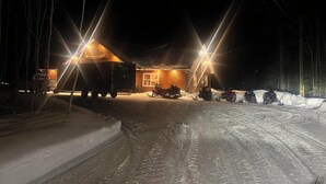 A wooden cabin with a snow-covered ground and a sled in front. - Bathurst New Brunswick Access to snowmobiles trail and ATV. (Saint-Laurent)
