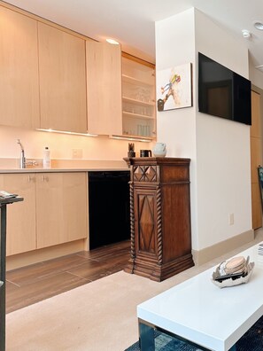A modern kitchen with wooden cabinets, a built-in dishwasher, and a white countertop. - Chic Apt w/parking - Walk to Capitol, Convention Center, museums & shops! (Denver)