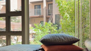 A bedroom with a large window, a bed with a white blanket, and a lamp. - Chic Apt w/parking - Walk to Capitol, Convention Center, museums & shops! (Denver)