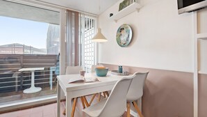 Un coin repas avec une table blanche, deux chaises, une suspension et une assiette décorative accrochée au mur.