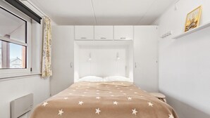 Une chambre à coucher avec un lit, une fenêtre, un radiateur et une armoire.