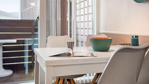 Un coin repas moderne avec une table blanche, un bol turquoise et une tasse à rayures.