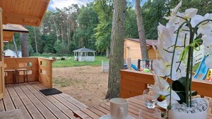 Een houten terras met een tafel en stoelen, een prieel en een speeltuin op de achtergrond.