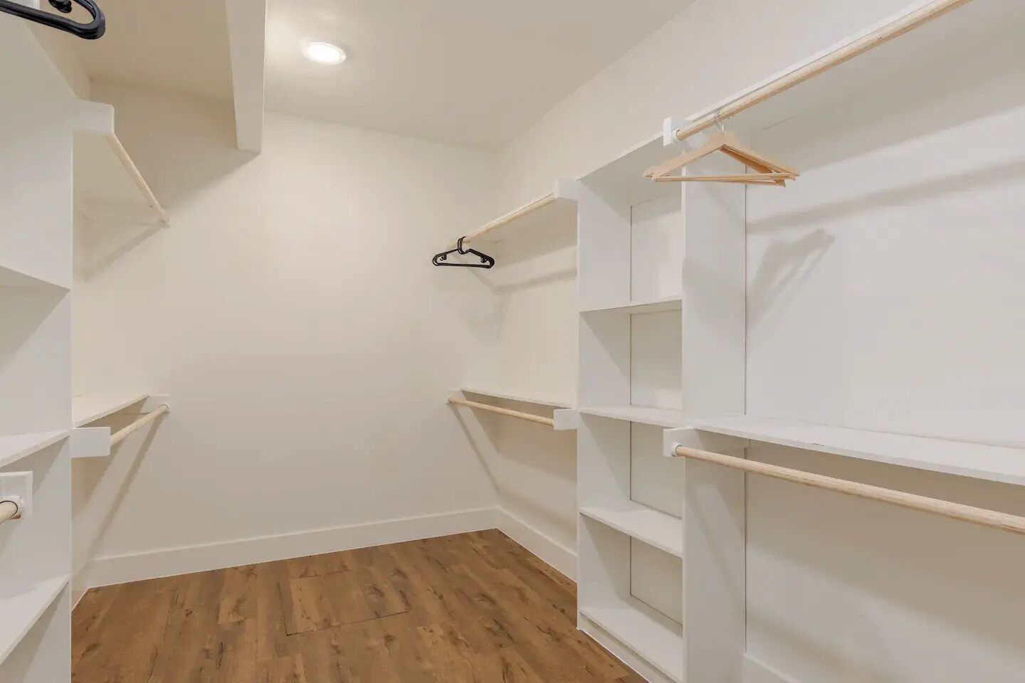 Un dressing avec des étagères blanches et un plancher en bois.