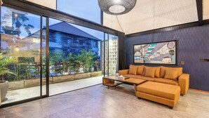 Ein modernes Wohnzimmer mit einer großen Glaswand, einem Sofa, einem Couchtisch und einer Pendelleuchte.