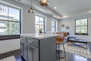 Eine moderne Küche mit einer zentralen Kochinsel, großen Fenstern und einer Sitzecke mit Sofa und Couchtisch.