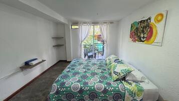 Ein Schlafzimmer mit Bett, einem Gemälde, einem Fenster mit Vorhängen und Blick ins Freie.