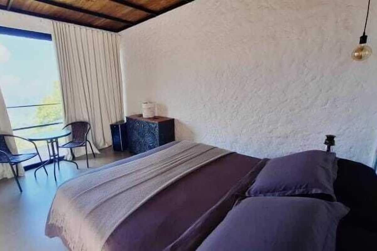 A bedroom with a bed, a desk, and a chair.