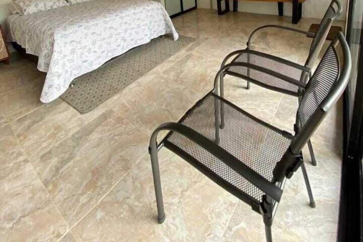 A bedroom with a bed, a chair, a desk, and a mirror.