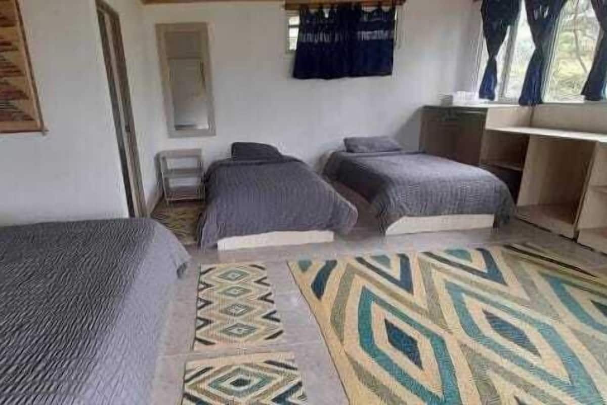 A room with two single beds, a small table, and a window with curtains.