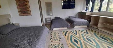 A room with two single beds, a small table, and a window with curtains.