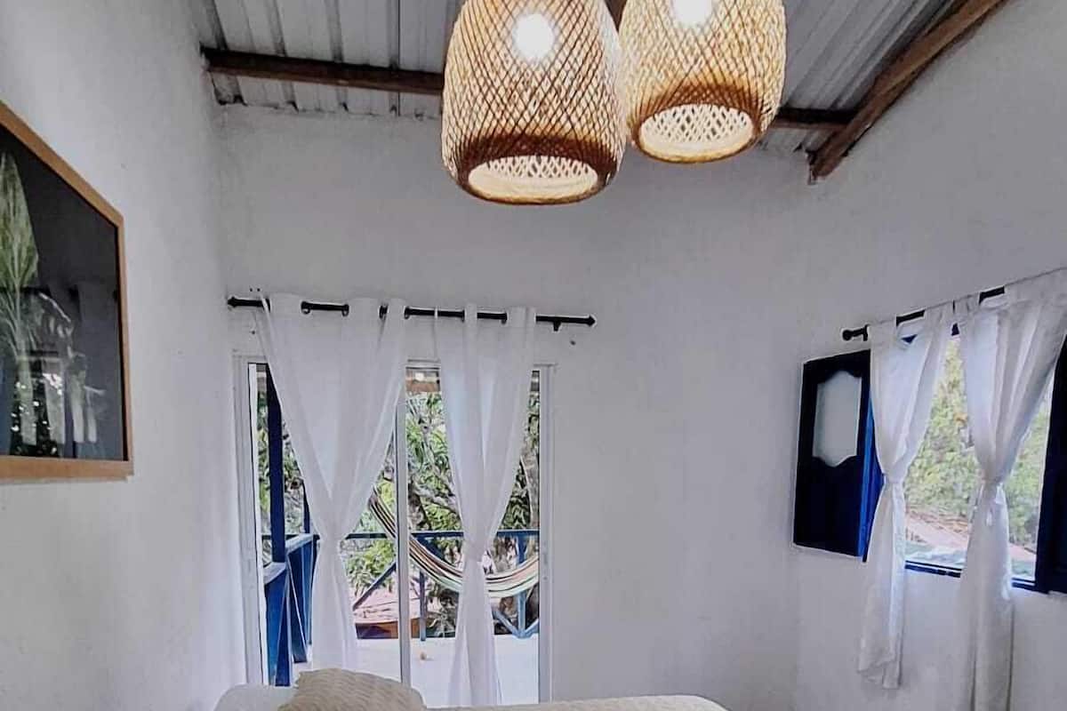 A bedroom with a bed, a nightstand, a lamp, and a window with curtains.