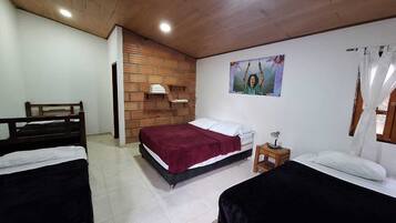 Ein Schlafzimmer mit zwei Betten, einer Wand aus Ziegelsteinen, einer Holzzielendecke und einem kleinen Nachttisch mit Lampe.