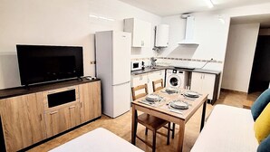 A compact living space with a kitchenette, a dining area, and a seating area with a sofa and a bed. - Playa Balerma II (Balerma)
