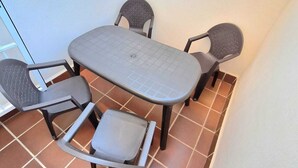 A small patio area with a table and four chairs. - Playa Balerma II (Balerma)