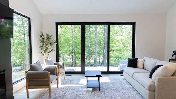 Ein modernes Wohnzimmer mit einer Couch, Sesseln, einem Couchtisch und einem Kamin.