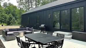 Eine moderne Außenpatio mit Esstisch und Stühlen, einer integrierten Sitzecke und einem Grill.