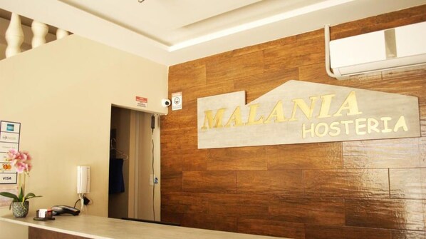 A reception area with a wooden wall and a sign that reads "MALANIA HOSTERIA".