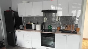 A modern kitchen with white cabinets, a black refrigerator, a microwave, a toaster, and a sink. - Stunning, remodeled condo in historic building along Odra River! (Szczecin)