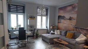 A modern living room with a grey sofa, a round coffee table, and a dining area with a table and chairs. - Stunning, remodeled condo in historic building along Odra River! (Szczecin)