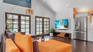 Een moderne woonkamer met een bank, televisie en keukenhoek.