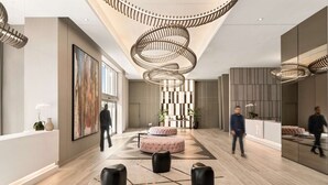 Un hall d’entrée spacieux agrémenté d’un lustre moderne, d’un grand tableau abstrait et d’un comptoir d’accueil.