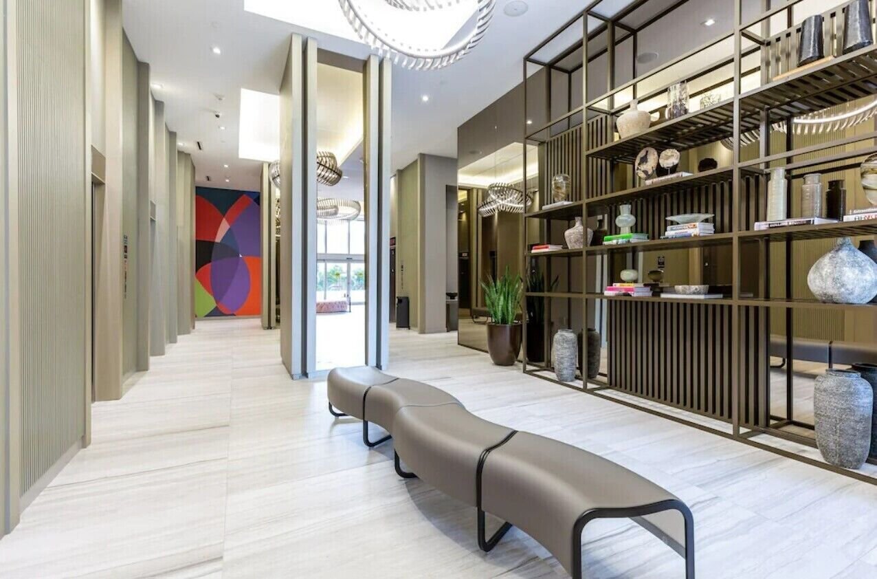 A modern interior with a long bench, a colorful abstract wall, and a shelving unit with decorative items.