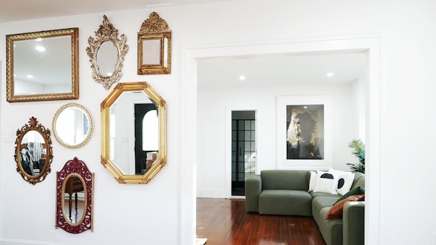 A room with a wooden floor, a green sofa, and various ornate mirrors on the wall. - Private Mountain Creek Getaway! (Vernon Township)