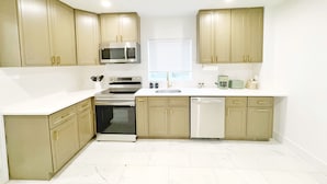 A kitchen with beige cabinets, a microwave, an oven, a dishwasher, and a sink. - Private Mountain Creek Getaway! (Vernon Township)