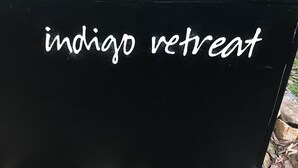 En svart skylt med texten ”indigo retreat” i vitt.