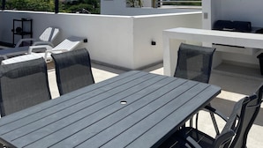 A rooftop terrace with a table and chairs, a grill, and a view of the city skyline. - DOI 45 Apartment (Playa del Carmen)