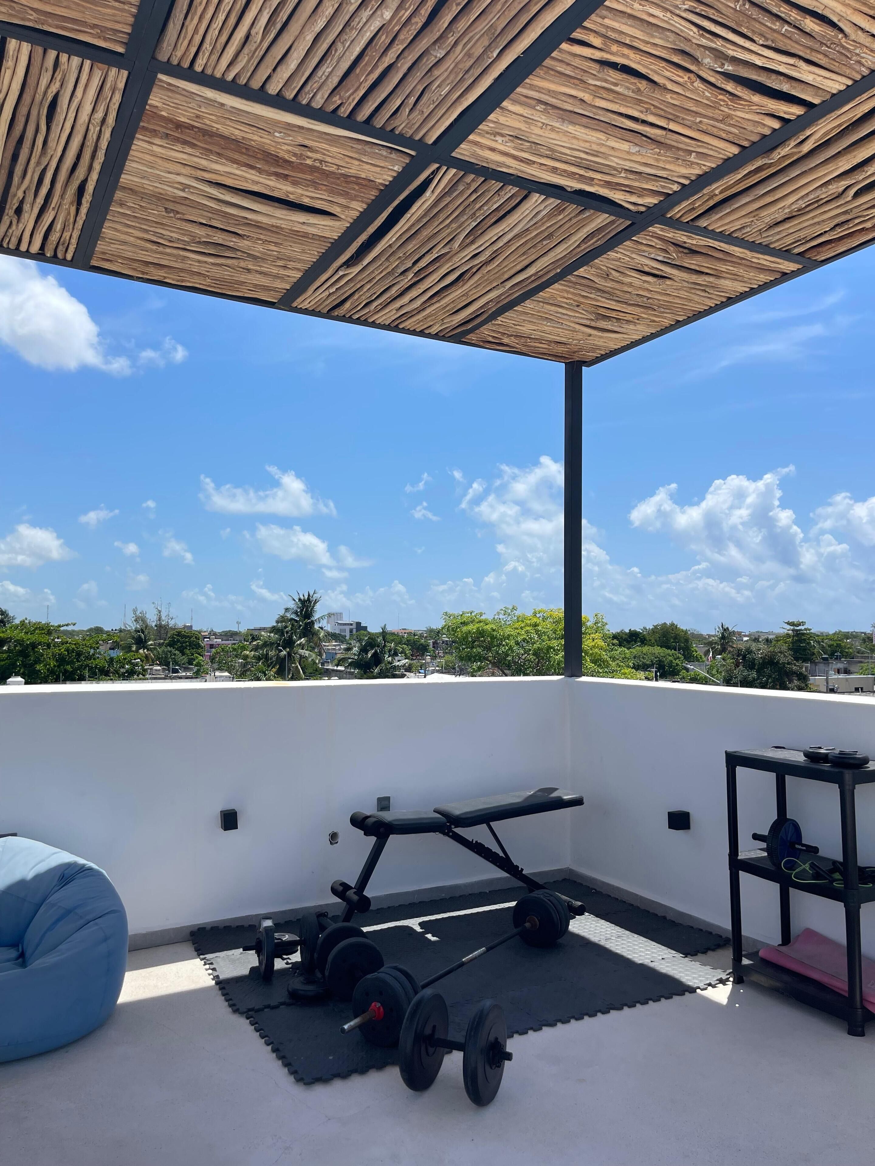 A rooftop gym with exercise equipment, a blue bean bag, and a view of the city skyline.