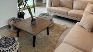 A modern living room with a beige sofa, a wooden coffee table, and a potted plant. - DOI 45 Apartment (Playa del Carmen)